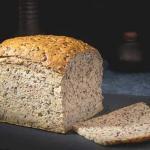 Kastenbrot mit lockerer, körniger Krume und goldbrauner Kruste auf dunkler Unterlage, eine Scheibe liegt abgeschnitten davor