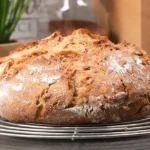 Rundes frisch gebackenes Körnerbrot mit knuspriger Kruste auf einem Abkühlgitter
