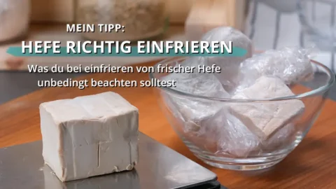 Frischer Hefewürfel auf einer Arbeitsfläche neben einer Glasschale mit eingewickelten Hefestücken