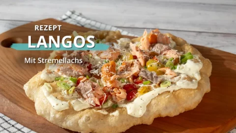 Ein mit Stremellachs belegtes Langos auf einem Holzbrett